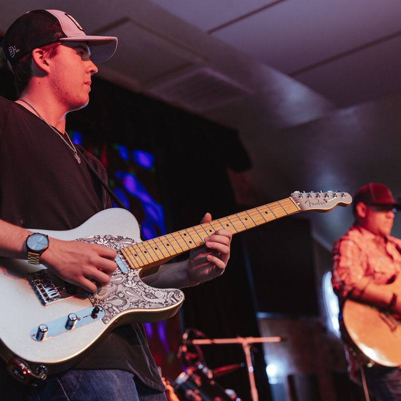 Two guitarists performing on a lit stage