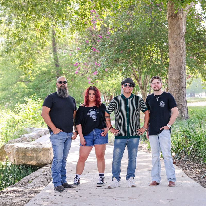 The four band members walking along a creekside path